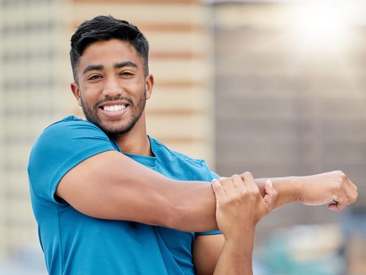 Smiling man stretching his shoulder