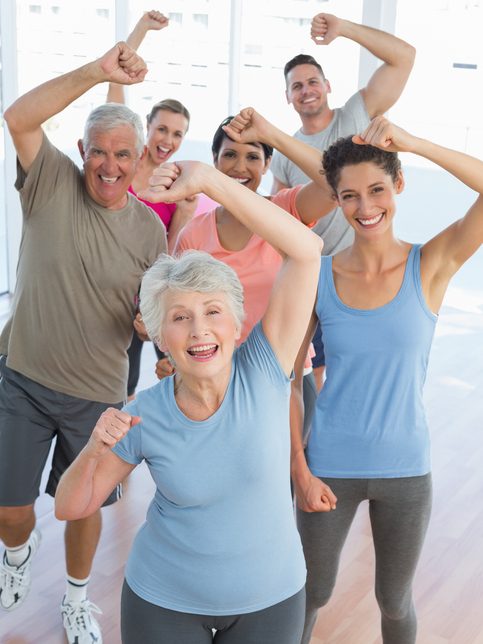 Portrait of smiling people doing power fitness exercise at yoga class in fitness studio