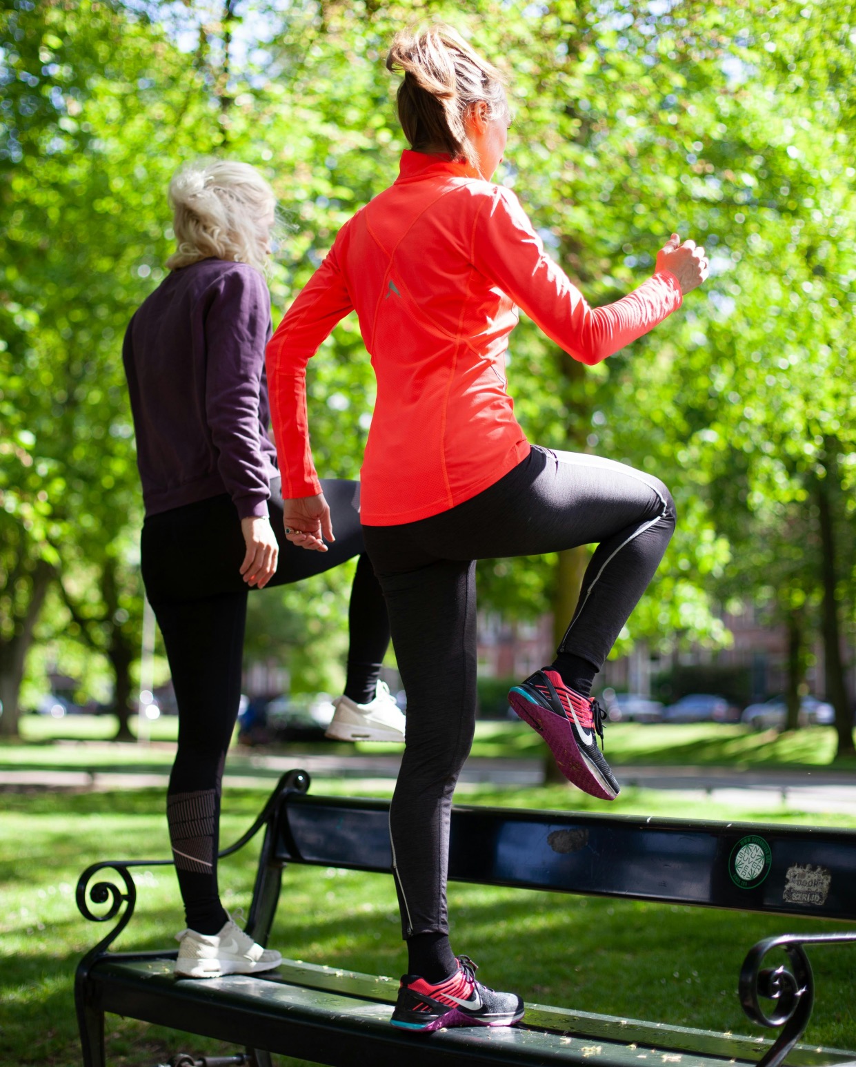 Two woman step up on a bench in the park for exercise