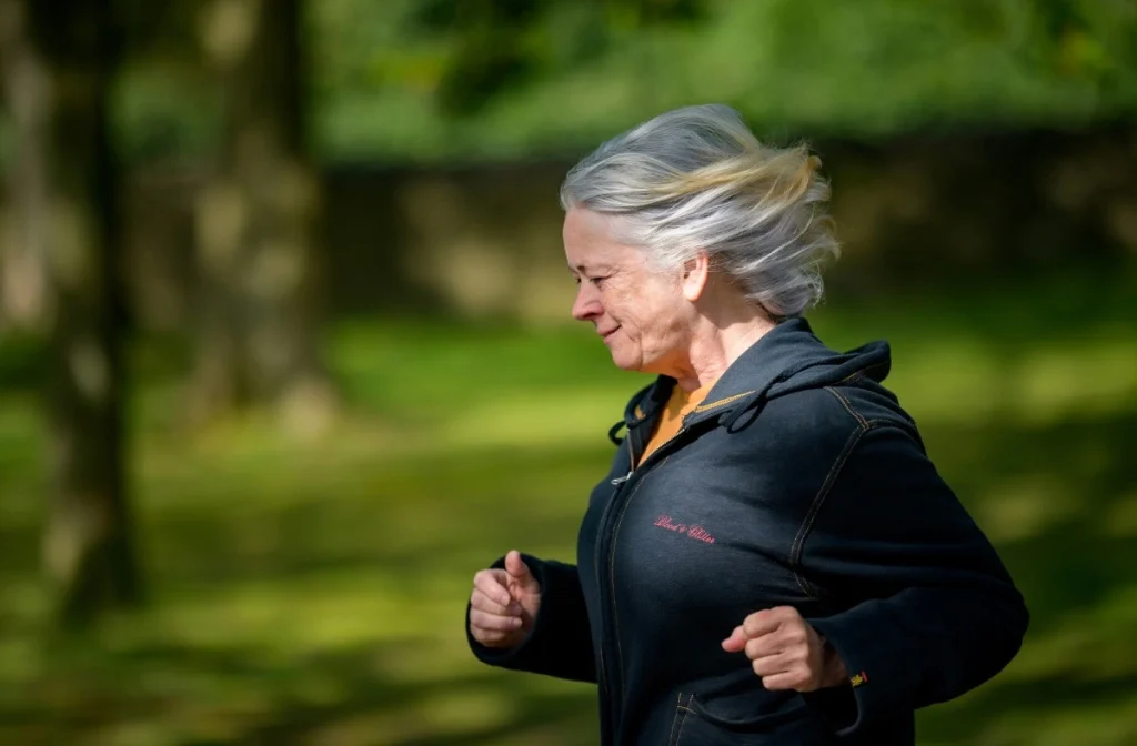 Woman with gray hair running through the park